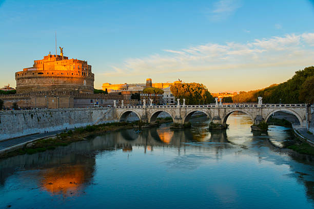 Rome, Italy - October 6, 2025: View of Sant'Angelo castle and bridge at sunset, reflected in the Tiber river.
