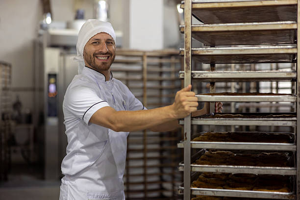 istock Happy baker pushing a cart with fresh bread at a bakery 2251241719