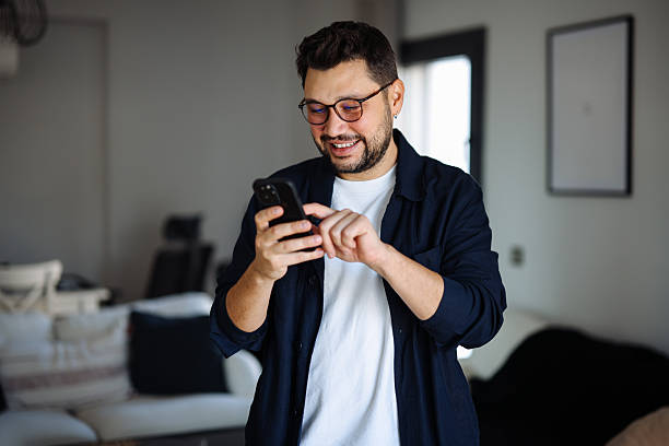 istock Young man smiling and using mobile phone at home 2251242234