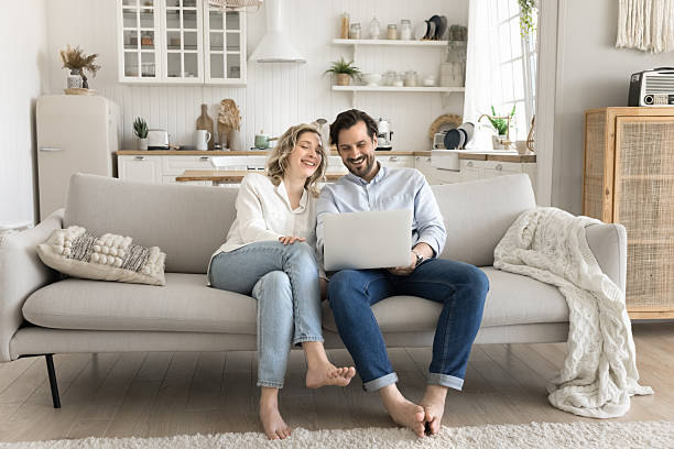 istock Smiling couple sitting on couch using notebook to shop online 2251244551