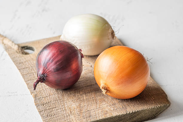 istock Three whole onions on rustic board showing red, yellow, and white varieties 2251245236