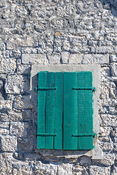 Green Shuttered Window Set in Rough Stone Wall of Rustic Old Building