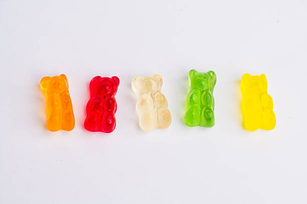 istock Different colored gummy bears arranged in a row on a table 2251248453