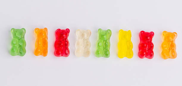 Colorful gummy bears arranged in a row on a white surface