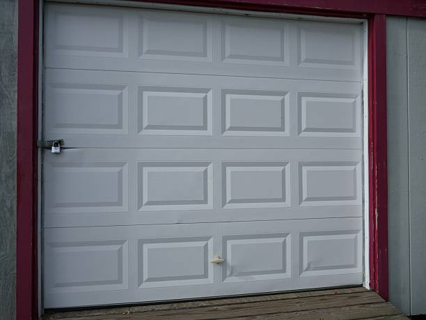 istock White garage door with red frame locked with padlock 2251254727