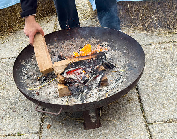 istock Male adding wood to outdoor fire pit with flames and ashes 2251255482