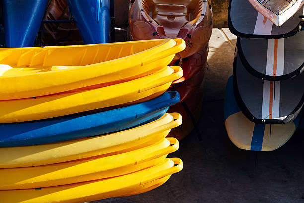 Colorful kayaks and canoes stacked neatly on a dock, showcasing vibrant hues of yellow, blue, and orange, creating a lively and inviting atmosphere for water sports enthusiasts