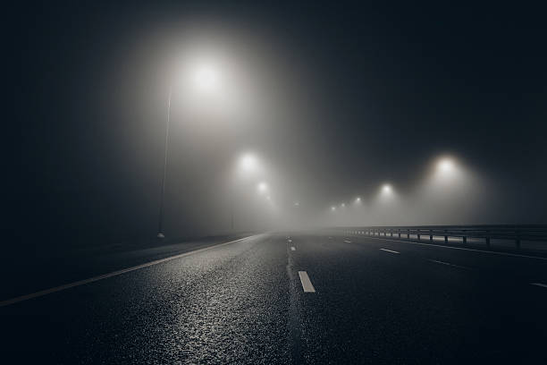 istock Foggy misty night road illuminated by street lights 2251260055