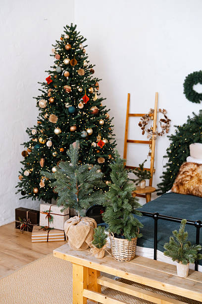 istock Festive decorated evergreen tree with presents and smaller trees indoors. 2251263571