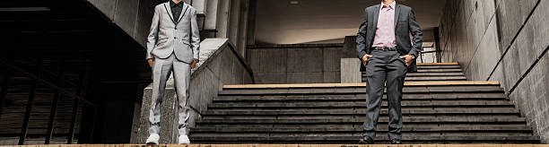 Two well-dressed men standing on concrete stairs in a modern urban environment