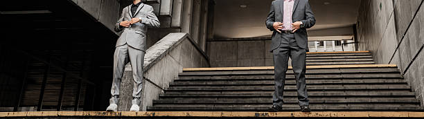 Two men wearing modern suits standing on concrete stairs in an urban setting