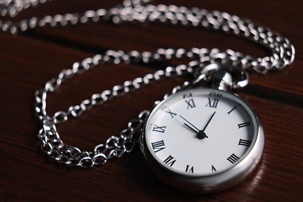 Closeup of a mid century pocket watch on a whitewashed wood background.