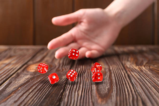 istock Woman throwing red dice on wooden table, closeup 2251273117