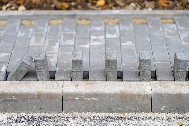 istock Gray concrete pavers in partial installation on edged pathway 2251273766