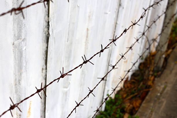 Barbed wire fence, a series of sharp-pointed wires stretched across a boundary for security or containment.