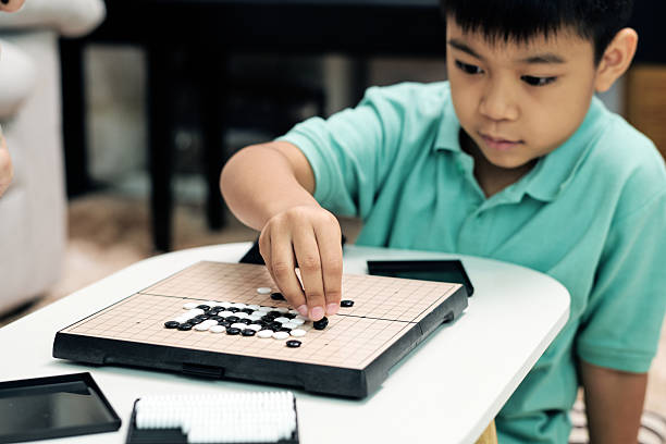 istock child placing a stone on a Go board during a strategy game at home, highlighting logical thinking, concentration, and educational family activities 2251276418