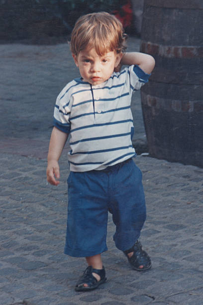 istock Photo taken in 1980s: Serious  walking little boy looking at the camera 2251277977