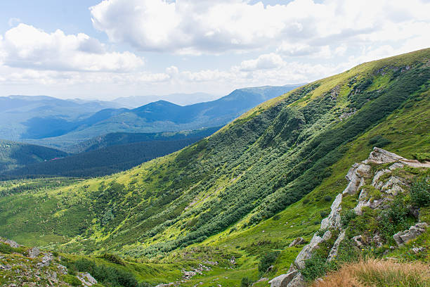 istock Mountain valley landscape with green hills and distant blue peaks under cloudy summer sky 2251278096