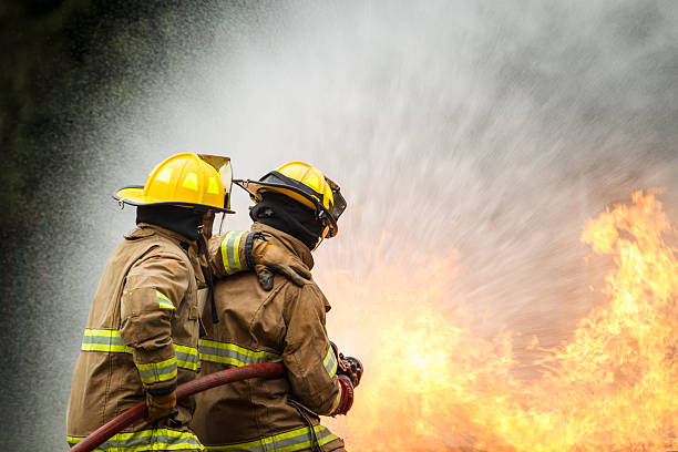 istock Fire fighter spraying water to control intense flames during fire training. 2251279972