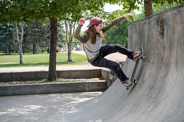 Non-binary skateboarder performing an action run on a quarterpipe in Winnipeg, showing balance and movement at an outdoor city skatepark. Active summer recreation and contemporary street culture.