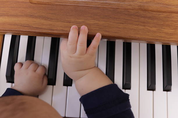 A baby pushing piano keys while exploring sound and cause-and-effect.