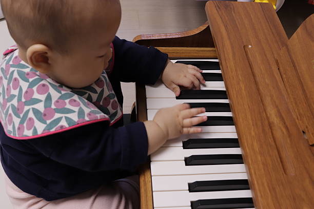 A baby touches the piano keys like a little musician, discovering rhythm and musical expression.