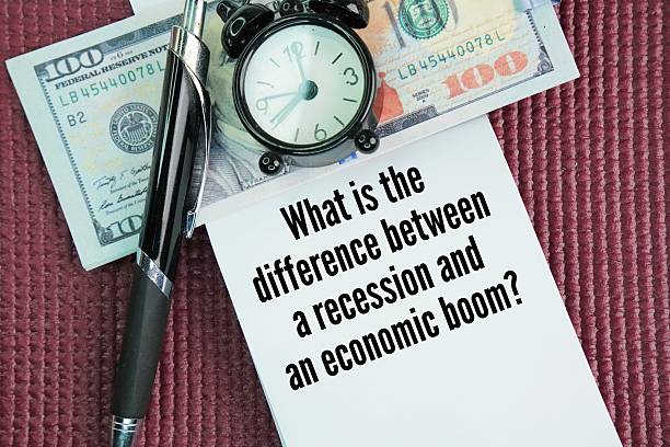 istock Paper money, bell clock, pen and paper with question words What is the difference between a recession and an economic boom? 2251285629