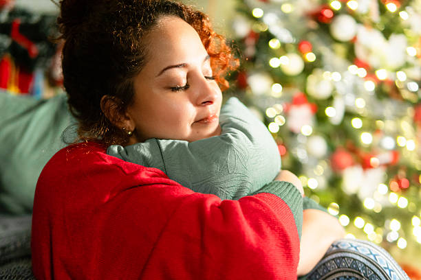 istock Woman embracing pillow feeling relaxed by christmas tree lights 2251288753