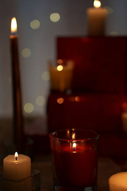 istock softly glowing candles with flickering flames on a dimly lit table, creating a warm and cozy atmosphere with a rich red background and subtle bokeh lights enhancing the tranquil vibe, hues 2251289405