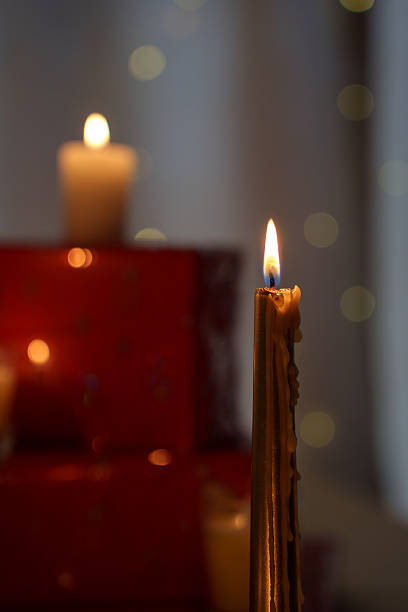 istock a golden candle softly glows with warm wax drips, surrounded by blurred red gift boxes and soft white bokeh, creating a serene and festive ambiance with subtle depth and focus, subtle, seasonal 2251289408