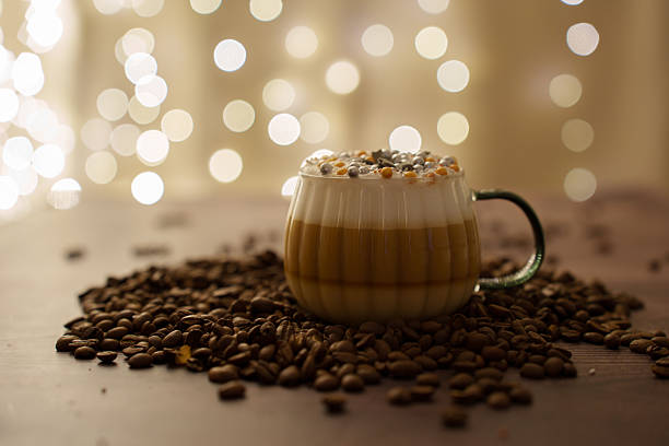 istock a cozy coffee scene featuring a layered latte with festive toppings, surrounded by scattered coffee beans against a backdrop of warm bokeh lights, creating a cozy atmosphere, inviting, caffeine 2251289533