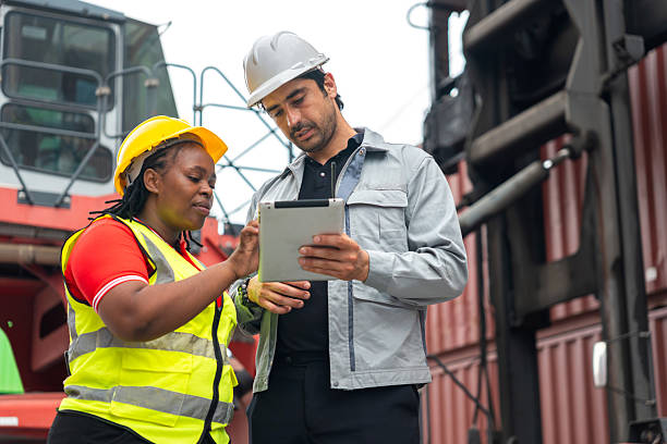 istock Engineers Discussing Data on Tablet at Shipping Container Yard, Two Workers Reviewing Order on Device, Logistics Supervisors Using Digital Tablet to Control Inventory and Cargo 2251289988