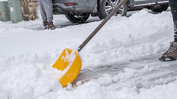 istock Snow cleaning service worker using a yellow shovel to clear snow from a driveway, showcasing winter maintenance and outdoor labor efforts 2251292258