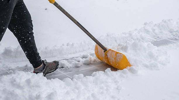 istock Snow cleaning service worker using a yellow shovel to clear snow from a walkway during a winter storm, showcasing effective snow removal techniques 2251292417