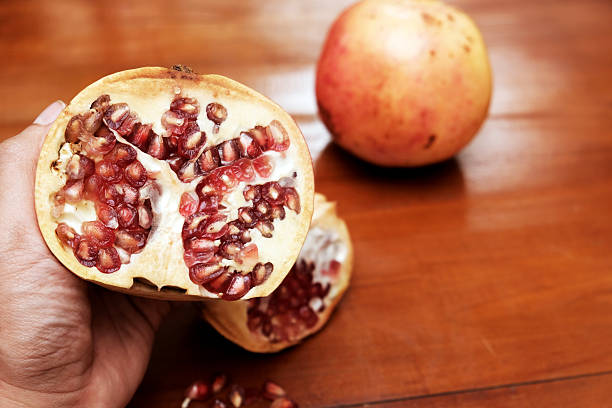 istock Broken ripe pomegranate in the hand over a wooden table 2251294462