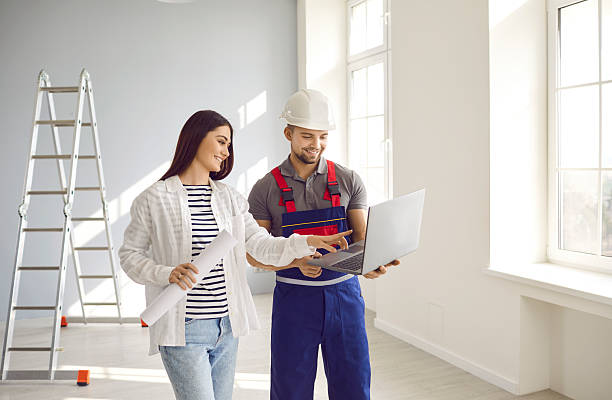 istock Happy young woman and engineer look at laptop computer and discuss house construction plan 2251297399
