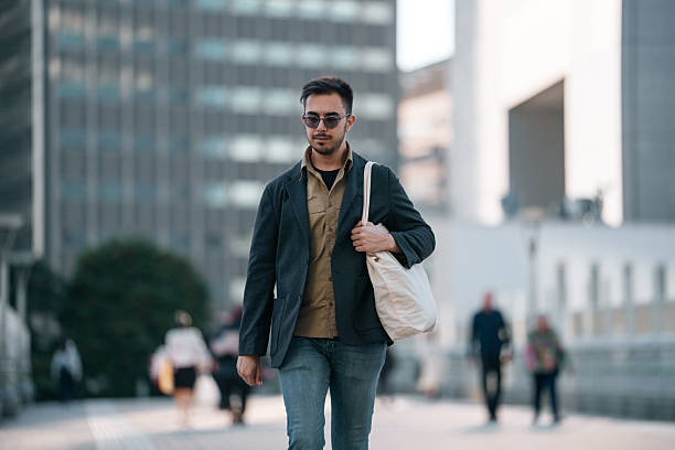 istock Man commuting through a modern city walkway with a reusable tote bag 2251300824