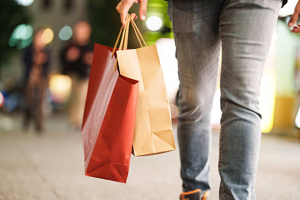 istock Hands holding shopping bags while walking through the city at night 2251300941
