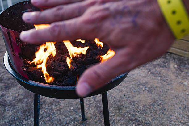 Hand burning on a charcoal barbecue flame grill