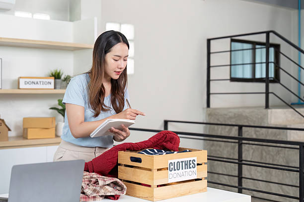 istock Clothes Donation. Young woman taking notes while organizing donations. 2251302621