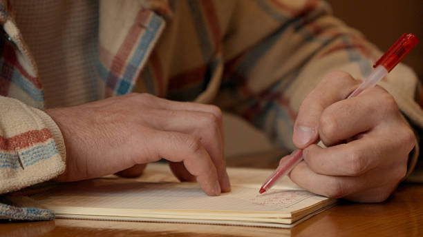 istock Close-up of a person's hand writing in a notebook on a wooden table 2251305000