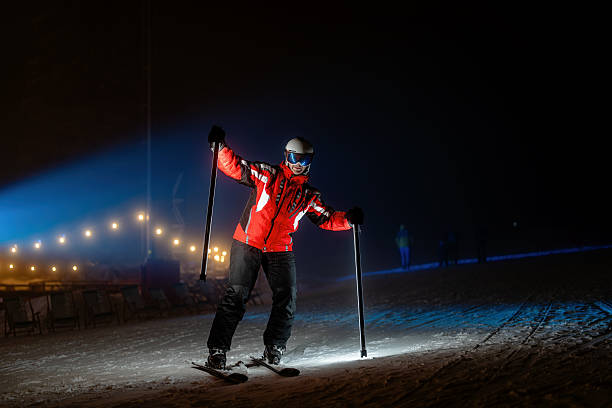A skier showcases their skills under dramatic night lighting. The striking use of glowing poles against a snowy backdrop enhances the perception of enjoyment and creativity. The vibrant outfit contrasts beautifully with the serene winter scene.