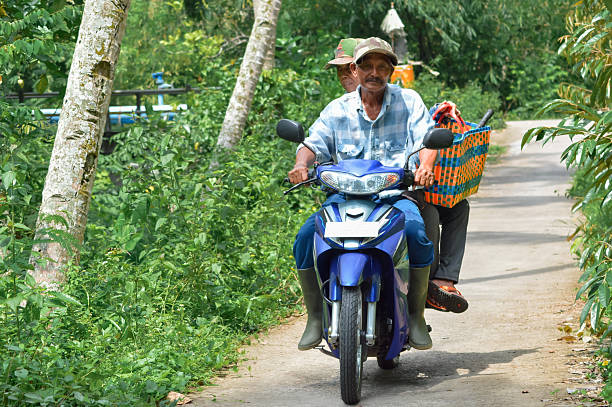 istock Elderly Couple Riding Scooter Down a Tree-Lined Rural Road 2251306531