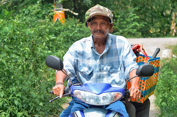 istock Elderly Man Riding a Scooter Through Green Village Field Path 2251306532