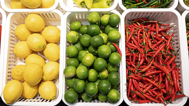Fresh lemon green lime red chili citrus fruit spicy pepper market stall plastic basket colorful produce food background natural ingredient Bright arrangement of fresh lemon, green lime
