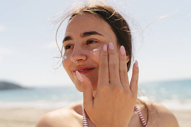 istock Young woman applying sunscreen on her face while at the beach 2251308249