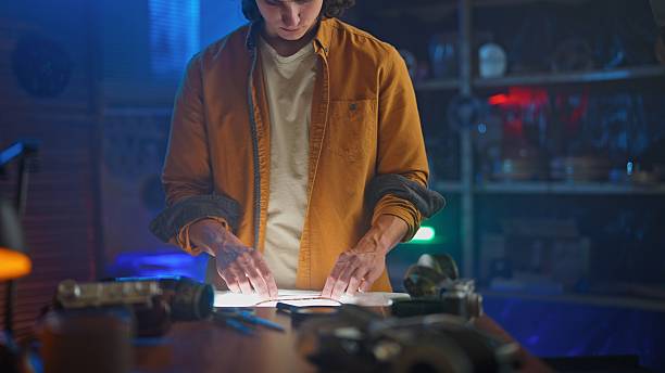 istock Young Man Studies Film Strip Under Soft Light in Dark Room 2251309005
