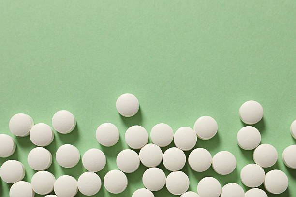 istock White medical pills on a colored background 2251311968