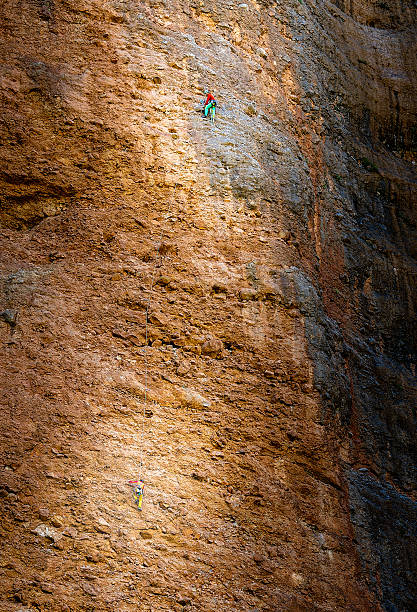 Conceptual shot showing the immense scale of a cliff compared to tiny human figures, representing resilience, determination, and overcoming obstacles
