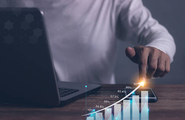 istock Young man with computer notebook and smartphone hand touching to visualize money growth The phone screen displays graphs and charts showing increasing investment and savings trends, along with an increased account balance 2251314209